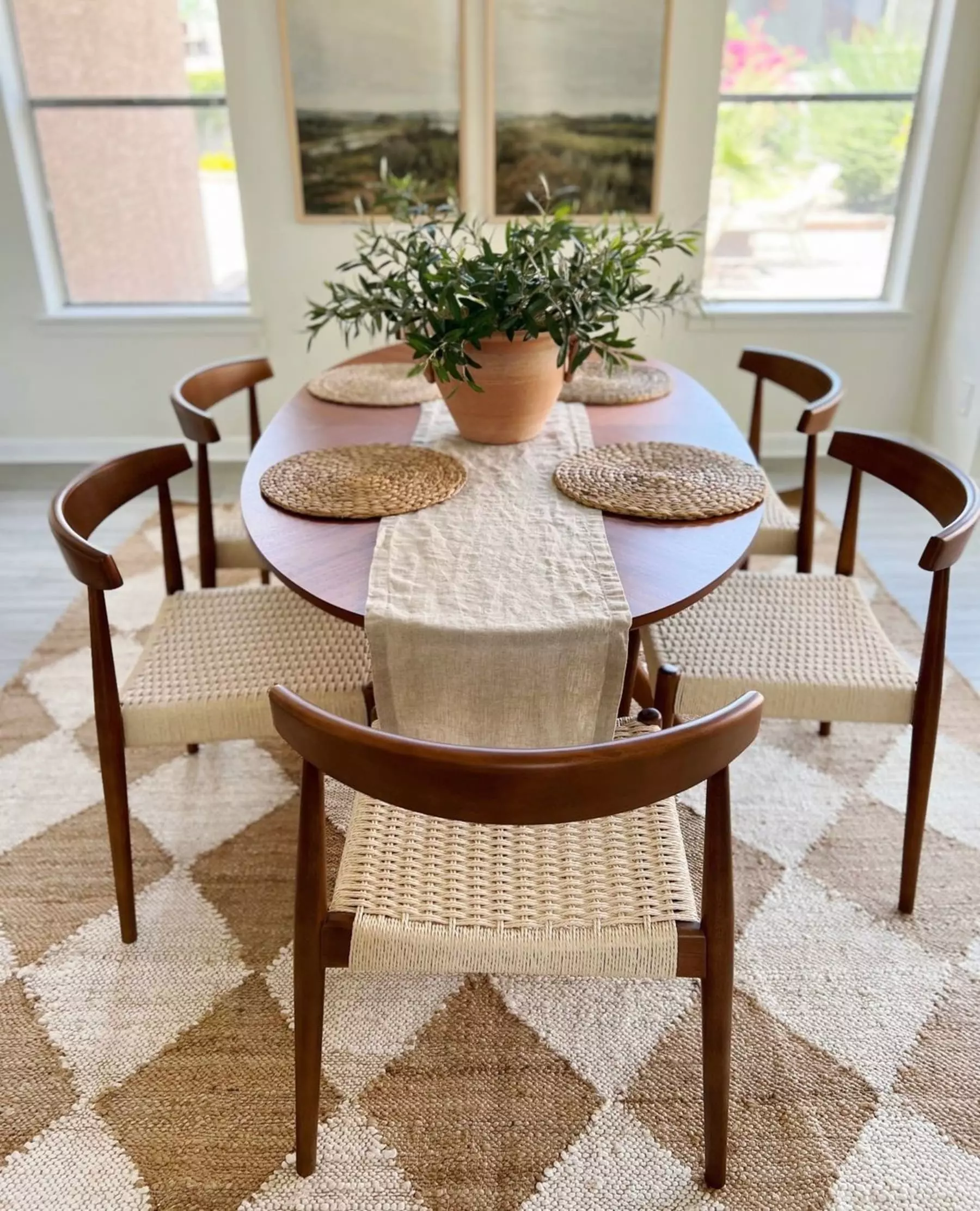 A wooden oval dining table with matching rattan chairs.