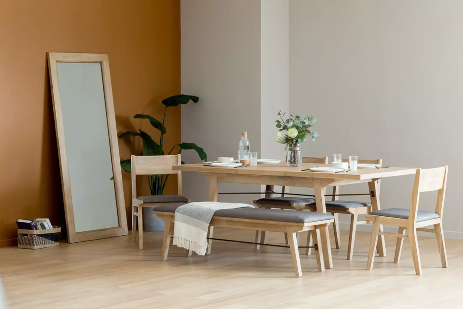 A mirror with a wooden frame is directly facing a matching dining table set.