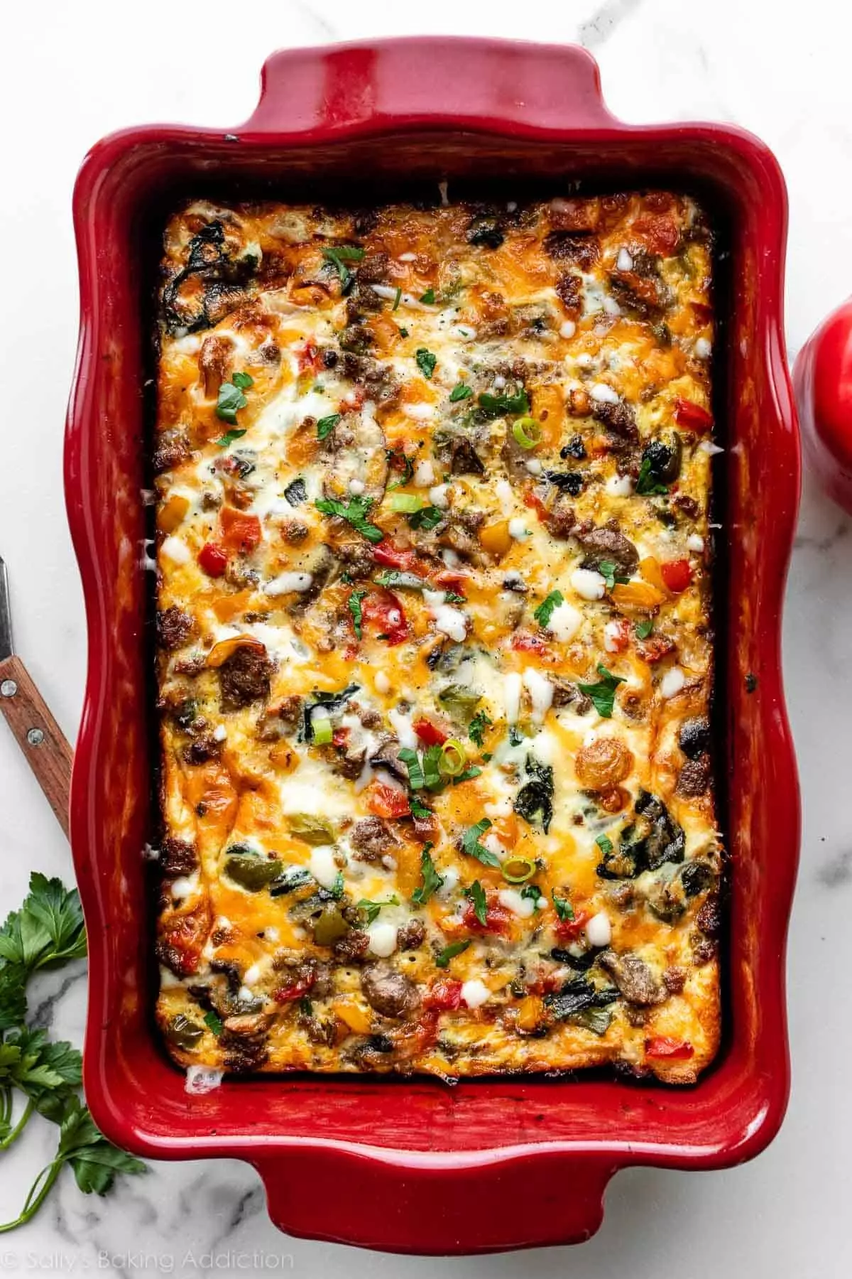 baked egg cheese and sausage breakfast casserole in a red casserole dish.