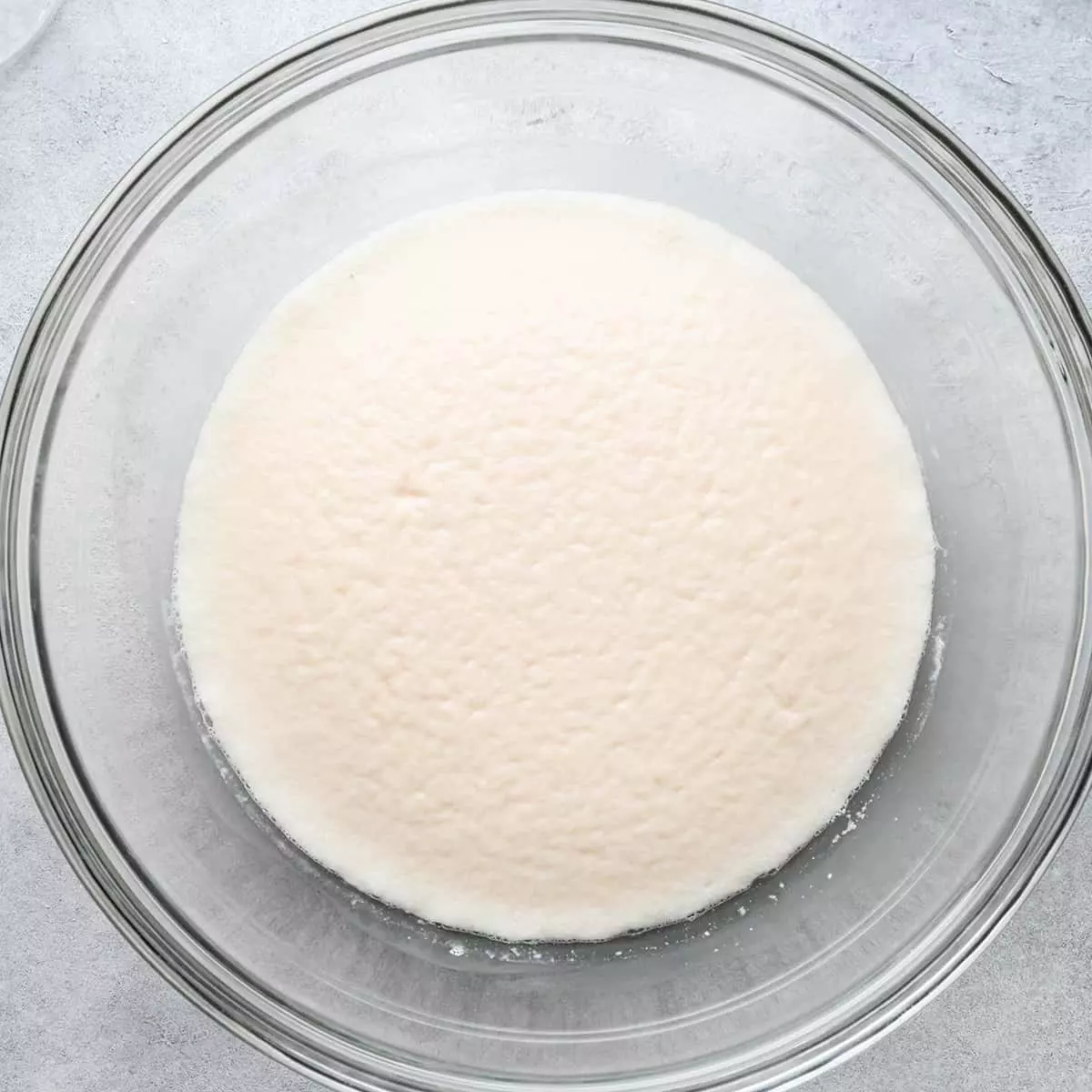 two photos showing pizza dough before and after rising in a glass bowl