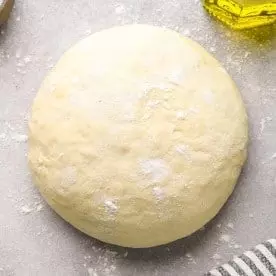 Homemade Pizza Dough Recipe dusted with flour; a cheese pizza made with this pizza dough recipe