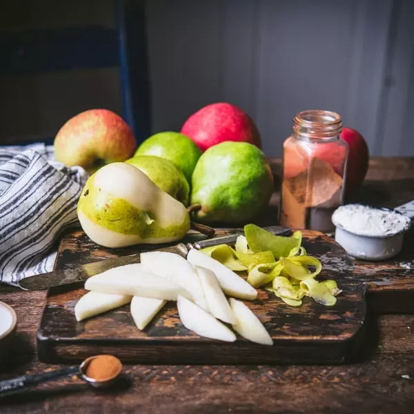 Sliced pears on a cutting board with apples in the background
