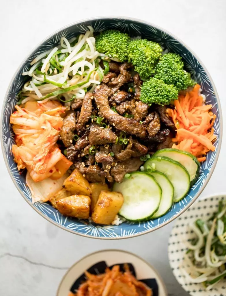 Korean beef steak rice bowl is loaded with tender and juicy strips of beef, marinated vegetable sides, and kimchi. Make it in under 30 minutes!
