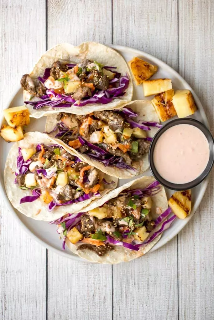 Fusion-style Korean beef steak tacos are made with tender, flavor-packed slices of beef and topped with caramelized pineapple, kimchi, and spicy mayo.