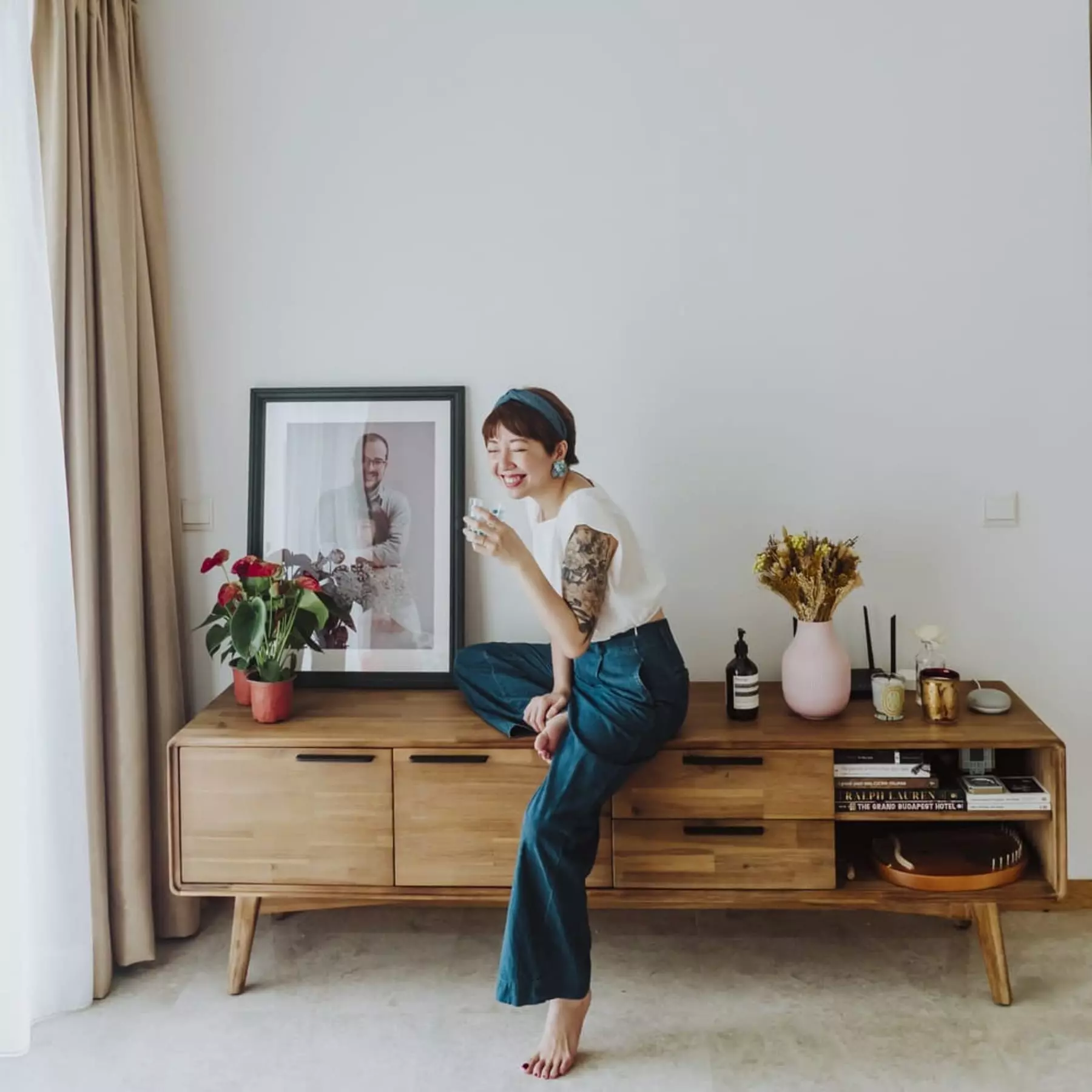 A person sitting on a wooden TV stand in the living room.
