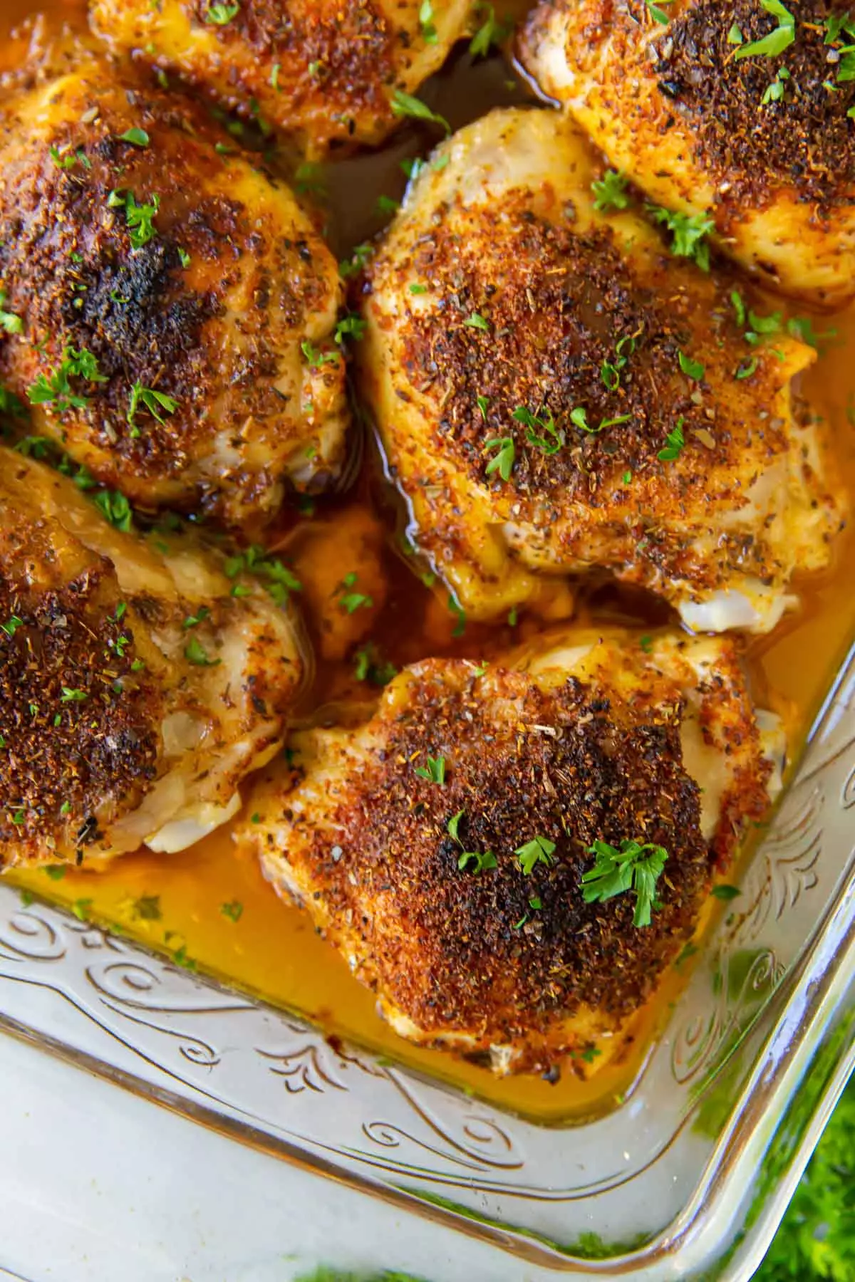 Close up of crispy bone-in oven-baked chicken thighs in a baking dish.